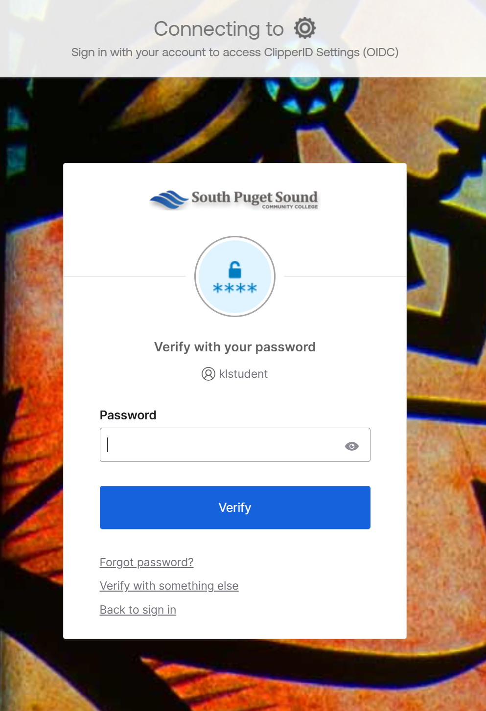 A white box above a colorful background. The South Puget Sound Community College logo is at the top of the page, and below reads "Verify with your password," and displays a username. Below is a blank passphrase box, and a blue "Verify" button. A link beneath the blue "Verify" button reads "Forgot password?"